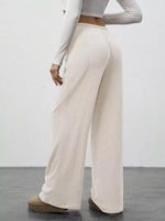 Person wearing beige ribbed wide-leg pants with a plain background
