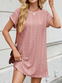 Woman wearing a pink lace dress against a light background