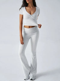 Woman wearing a white outfit with a V-neck top and wide-leg pants on a light gray background