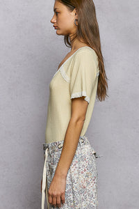 Woman wearing a light-colored top and floral pants against a gray background