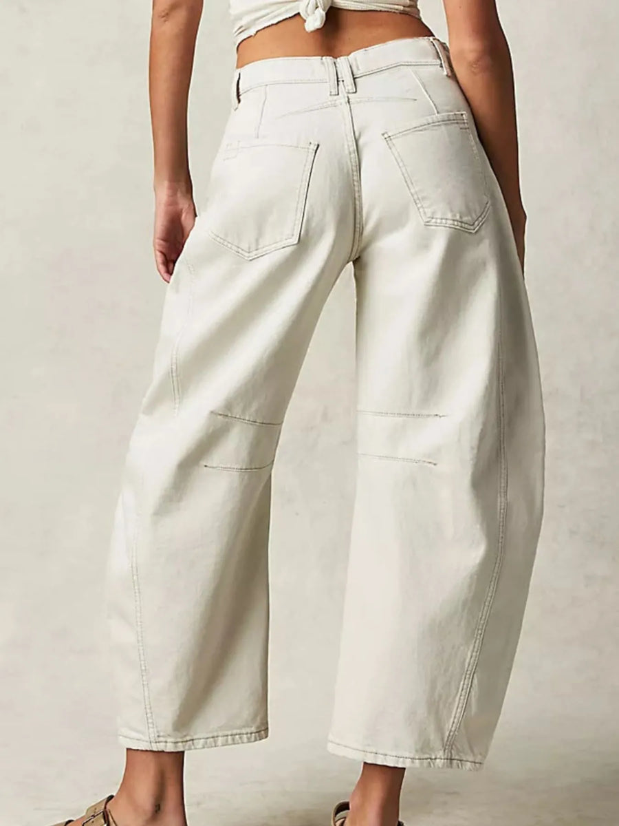 Person wearing light-colored wide-leg jeans on a plain background