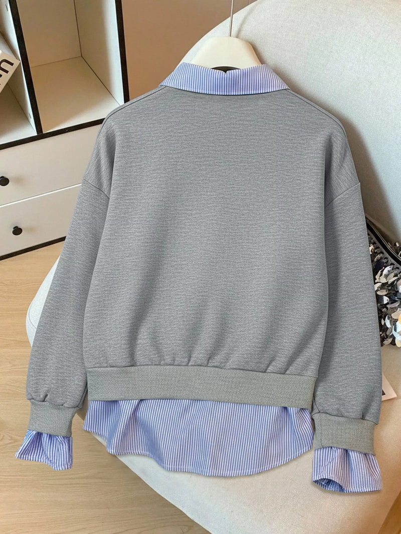 Gray sweater over a blue striped shirt on a mannequin against a neutral background