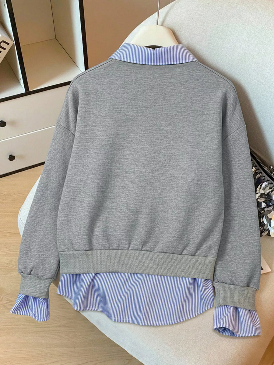 Gray sweater over a blue striped shirt on a mannequin against a neutral background