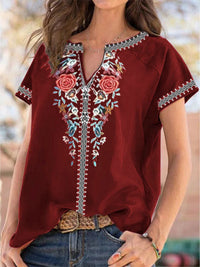 Red embroidered blouse worn by a person with a blurred outdoor background