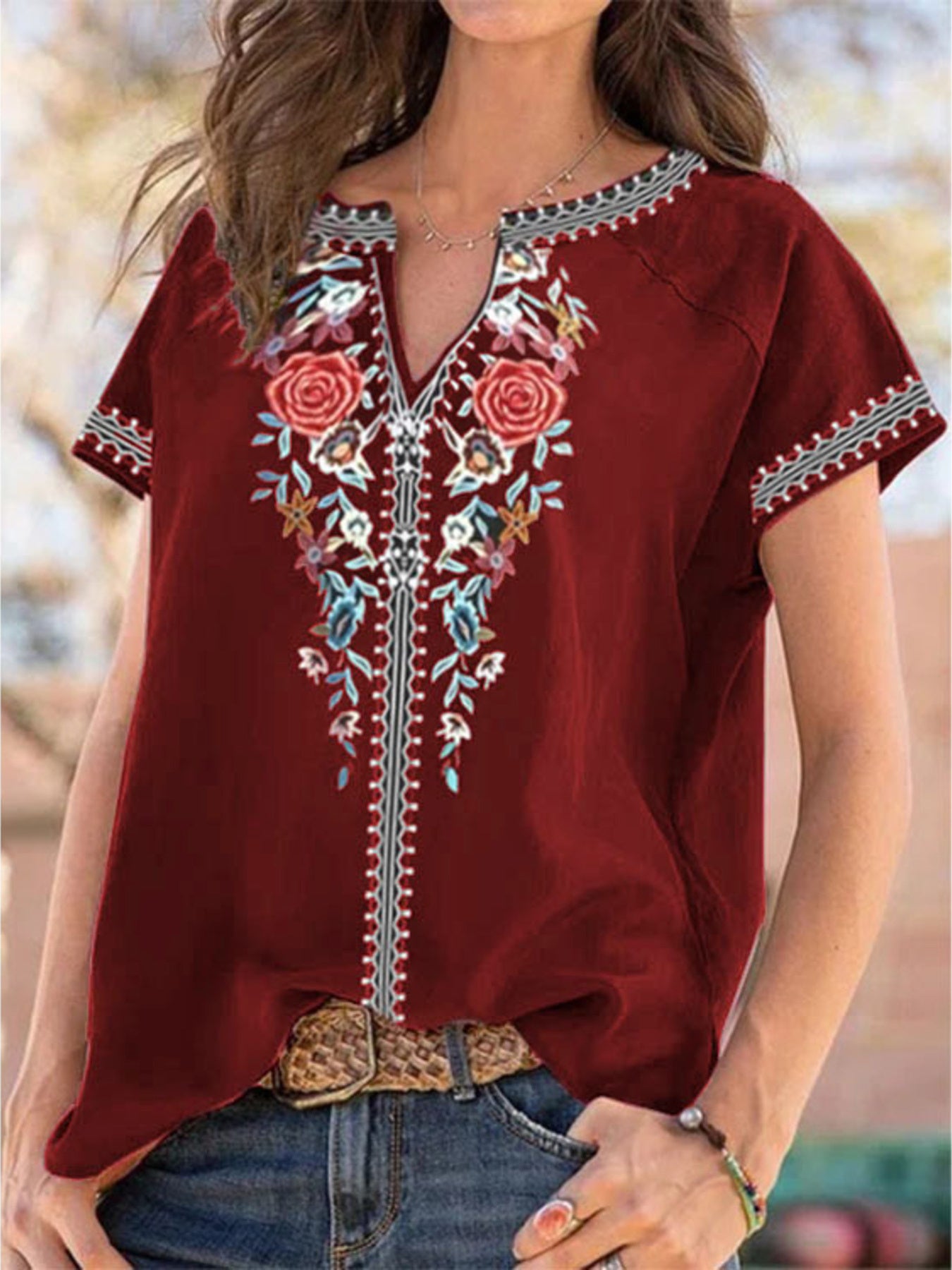 Red embroidered blouse worn by a person with a blurred outdoor background