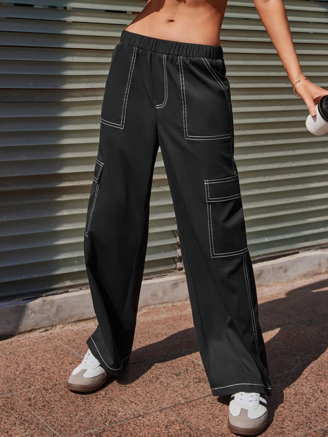 Person wearing black cargo pants standing against a metallic shutter.