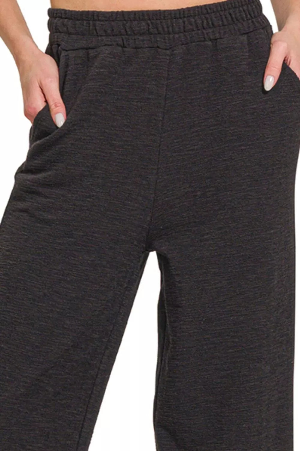 Dark gray sweatpants worn by a person on a white background