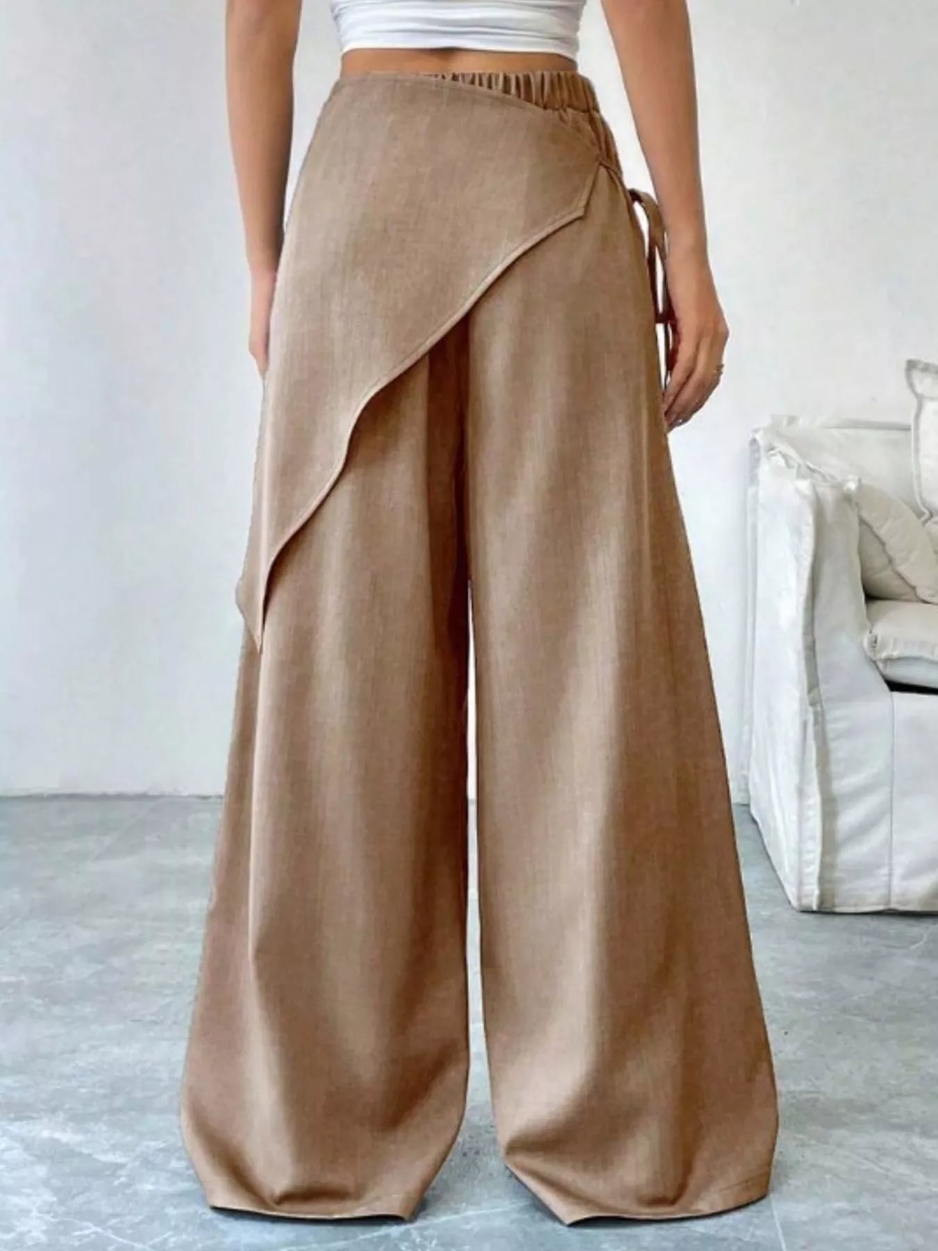Person wearing beige wide-leg pants in a minimal indoor setting