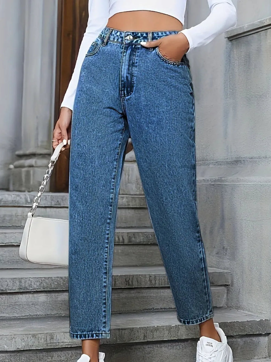 Person wearing blue jeans and a white top, standing on stone steps.