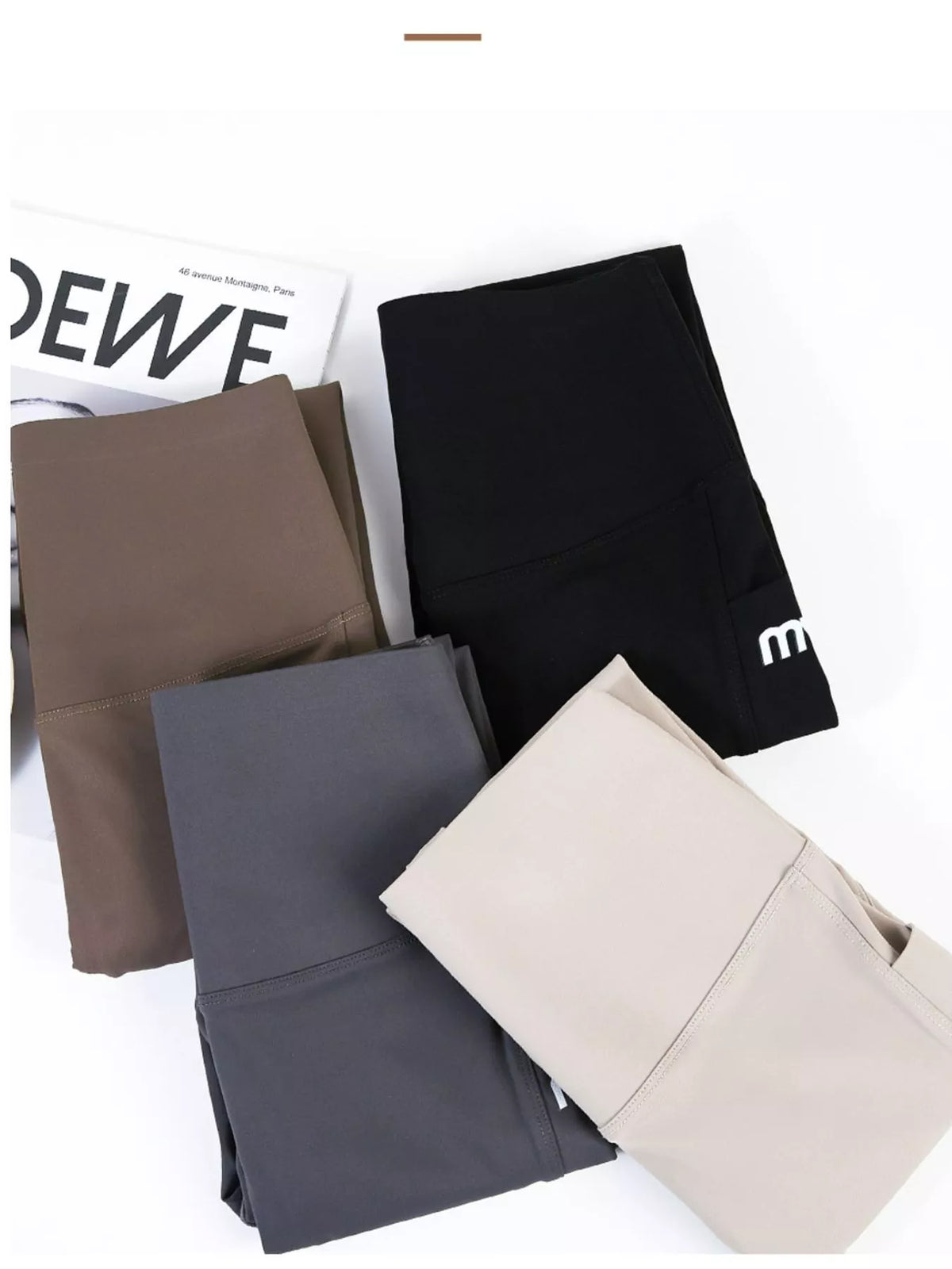 Four pairs of folded leggings in different colors (black, brown, dark gray, and beige) arranged on a white background with a magazine prop.