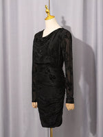 A black long-sleeve cowl-neck dress with floral lace applique, displayed on a cream mannequin with a gold neck cap against a light gray curtain backdrop.