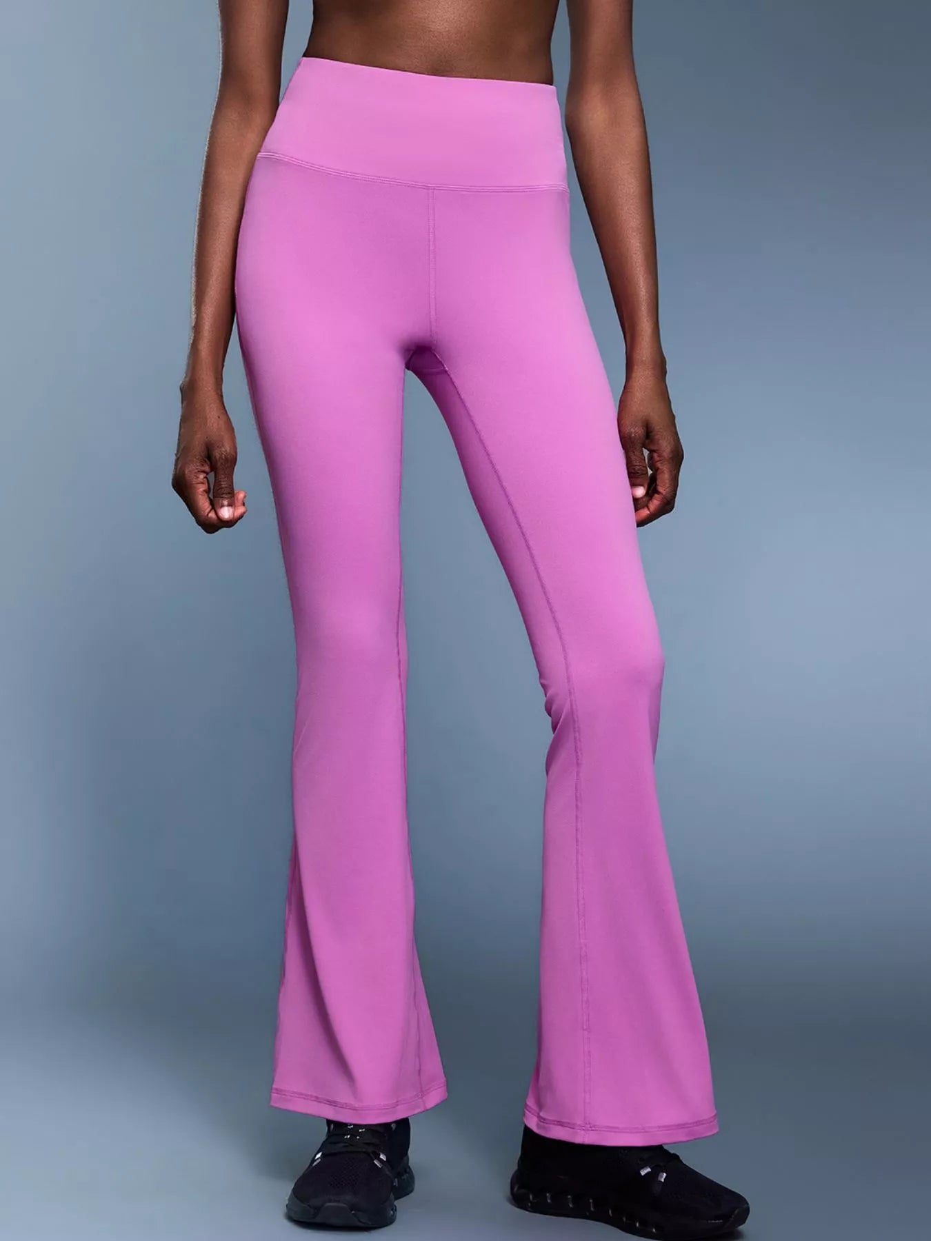 Person wearing pink flared pants on a gray background