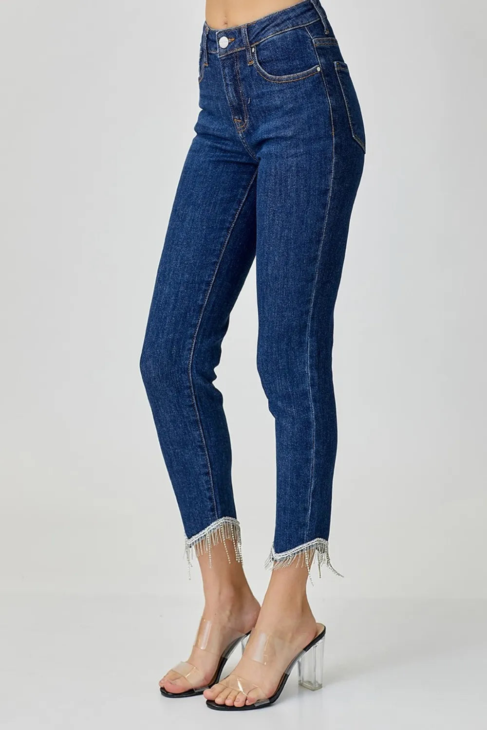 Blue jeans with fringe details on a white background