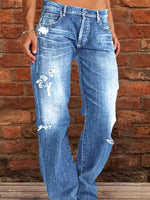 Blue distressed jeans worn by a person against a brick wall.