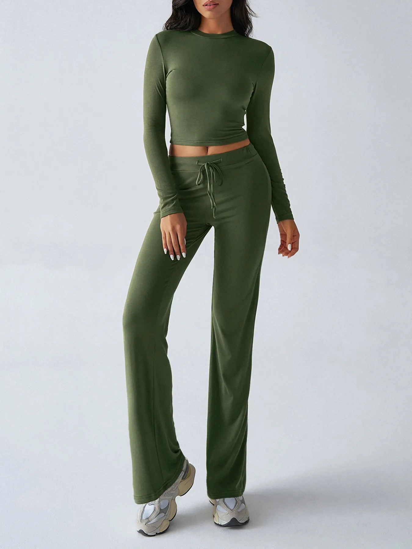 Person wearing a green long-sleeve top and matching pants on a white background