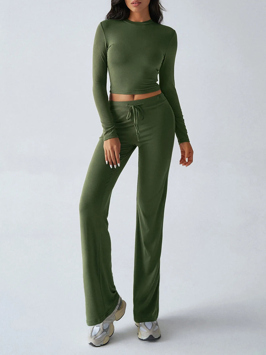 Person wearing a green long-sleeve top and matching pants on a white background