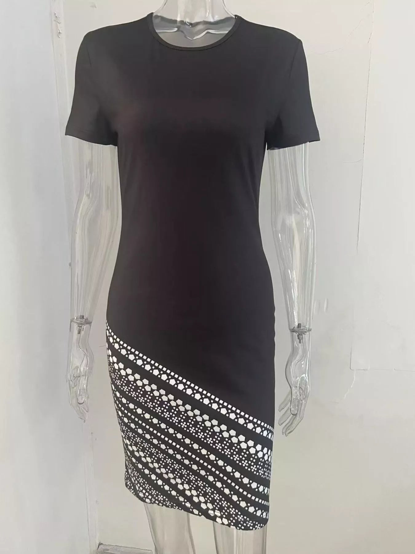 Black dress with a patterned hem on a transparent mannequin against a white background