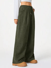Green wide-leg pants worn by a person on a white background