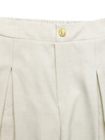 Close-up of beige pants with a gold button on a white background