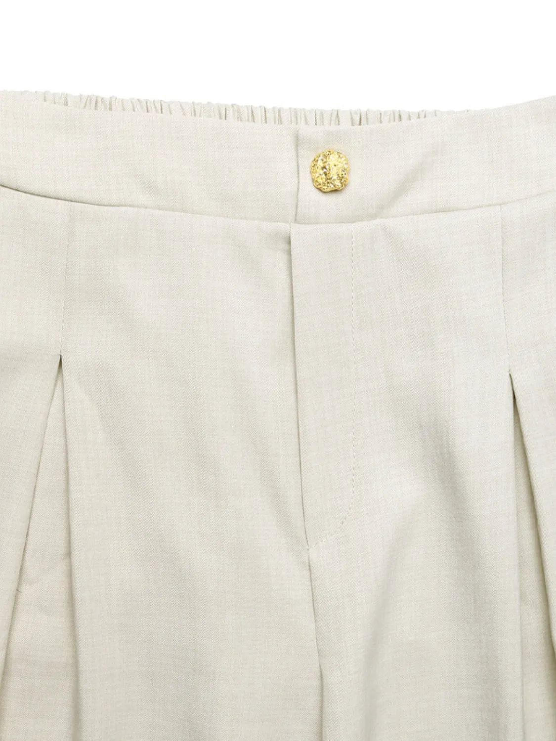 Close-up of beige pants with a gold button on a white background