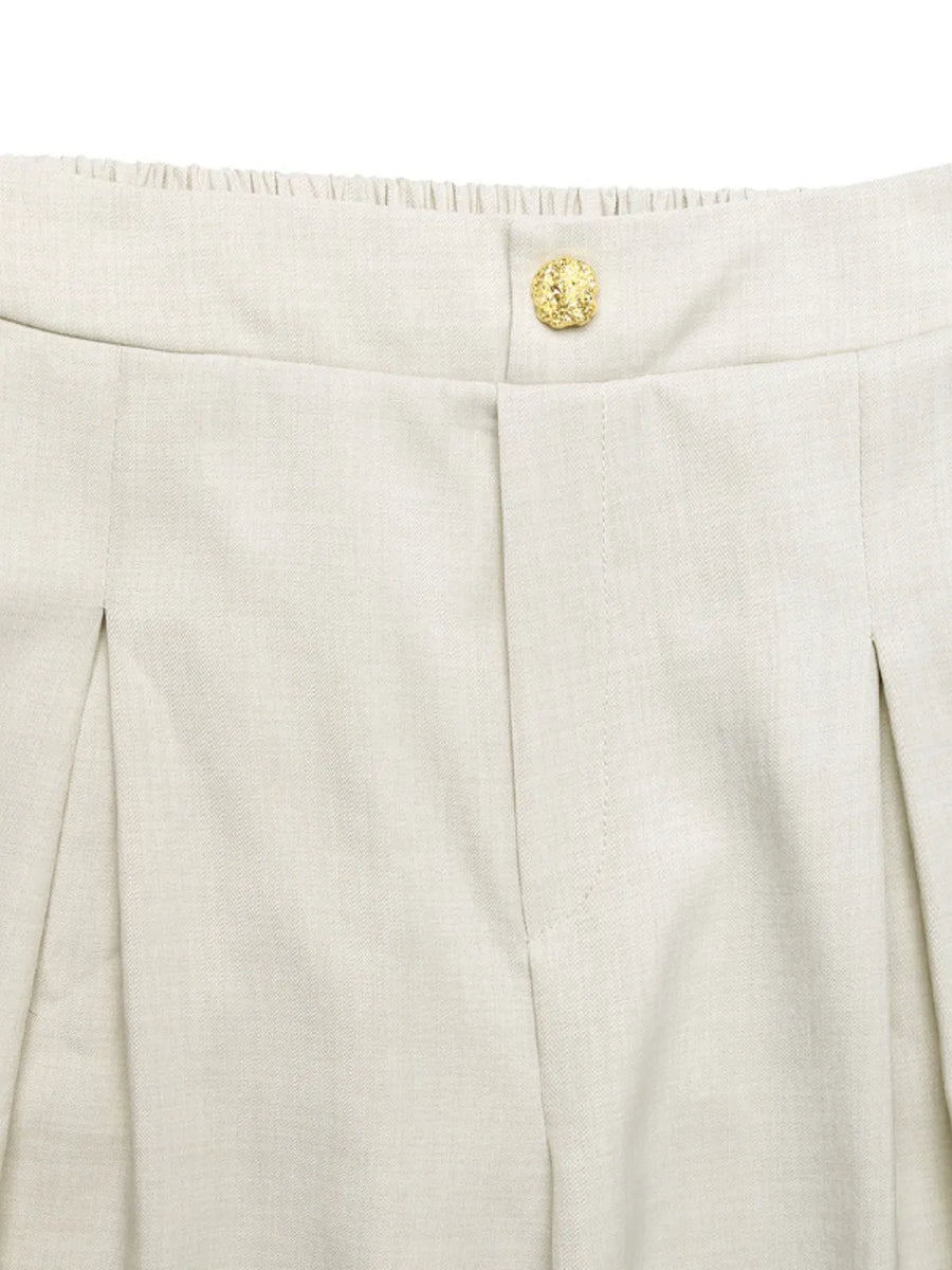 Close-up of beige pants with a gold button on a white background