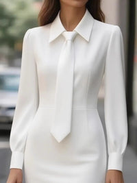 White dress with a tie worn by a person on a blurred street background