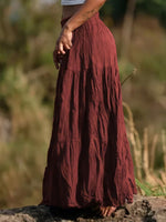 Person wearing a long burgundy skirt standing outdoors with a blurred natural background