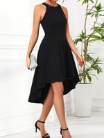 Woman wearing a black dress with an asymmetrical hem in a minimalistic setting.