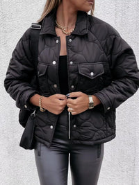 Person wearing a black quilted jacket on a light gray background