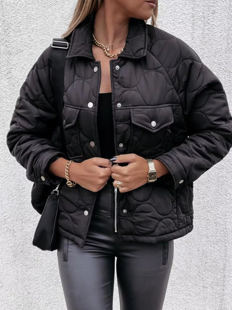 Person wearing a black quilted jacket on a light gray background