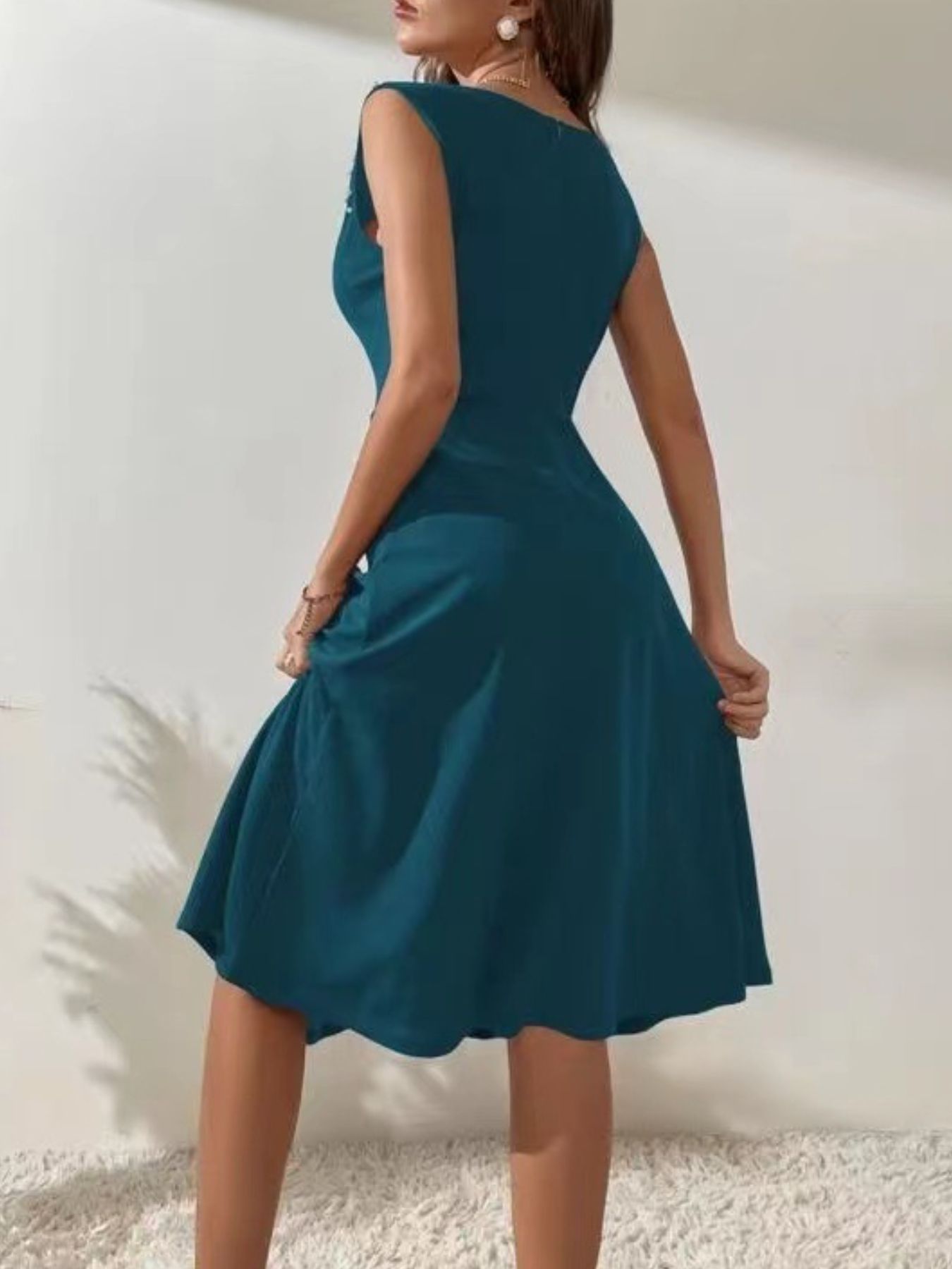 Teal dress worn by a person on a plain background