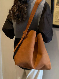Brown leather bag carried by a person against a neutral background