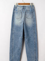 Blue jeans hanging on a wooden hanger against a white background