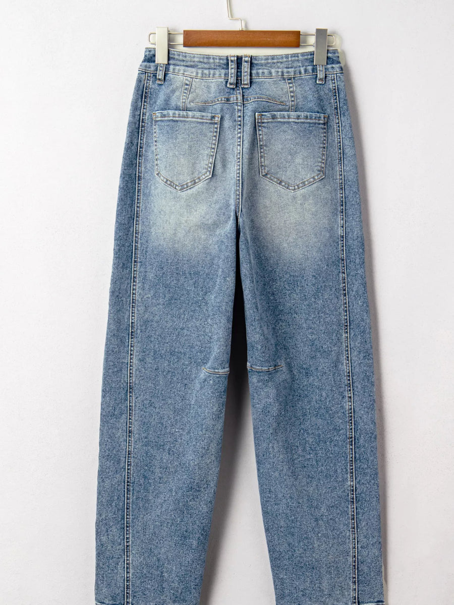 Blue jeans hanging on a wooden hanger against a white background