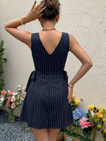 Woman wearing a navy pinstripe dress with flowers in the foreground