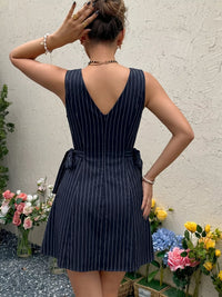 Woman wearing a navy pinstripe dress with flowers in the foreground