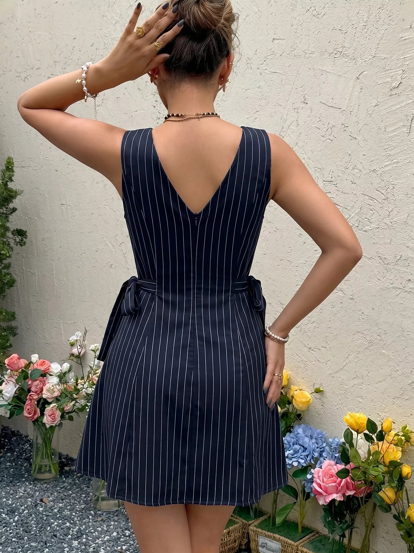 Woman wearing a navy pinstripe dress with flowers in the foreground