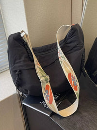 Black bag with a colorful floral strap on a chair