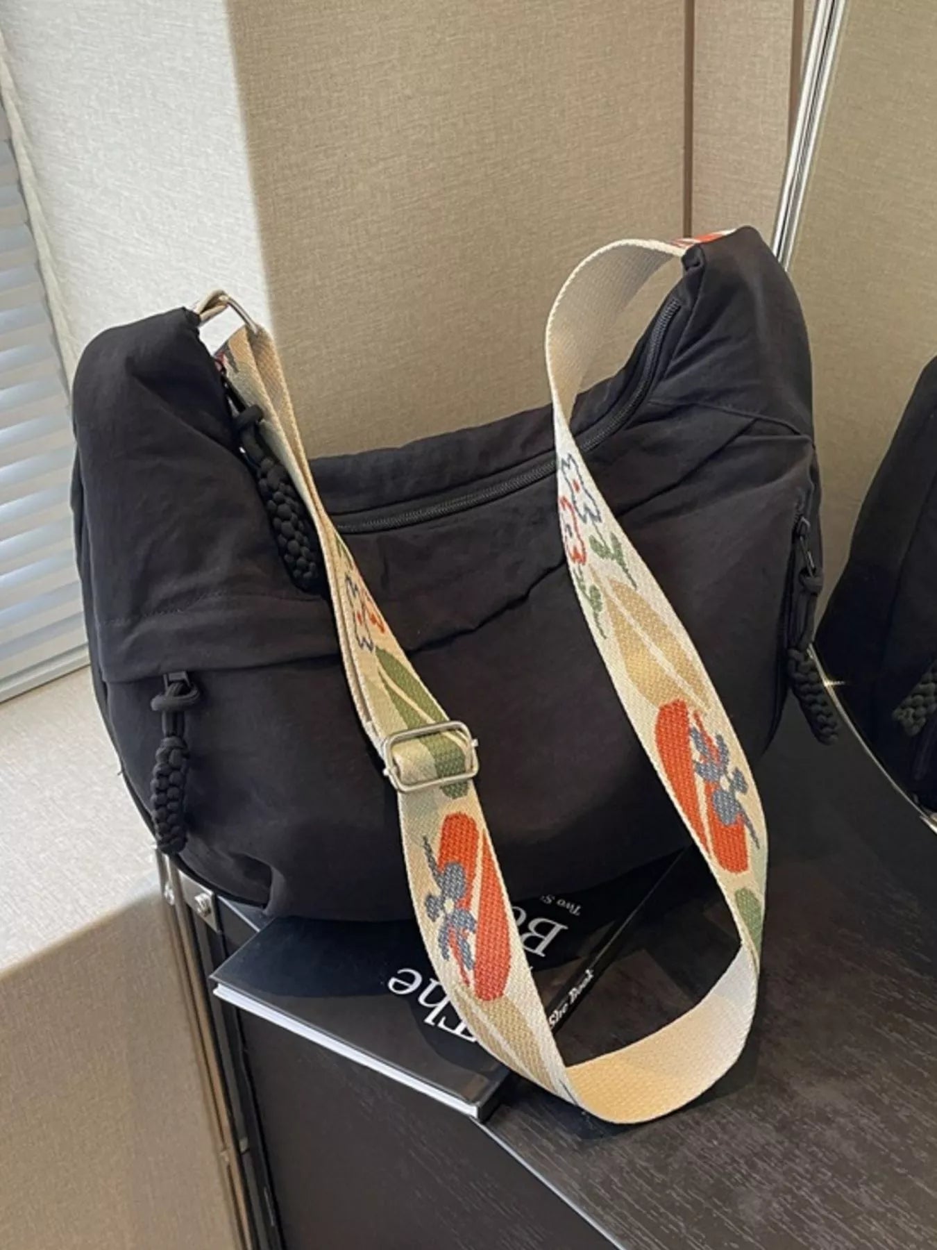 Black bag with a colorful floral strap on a chair