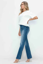 Woman wearing a white top and blue jeans on a white background