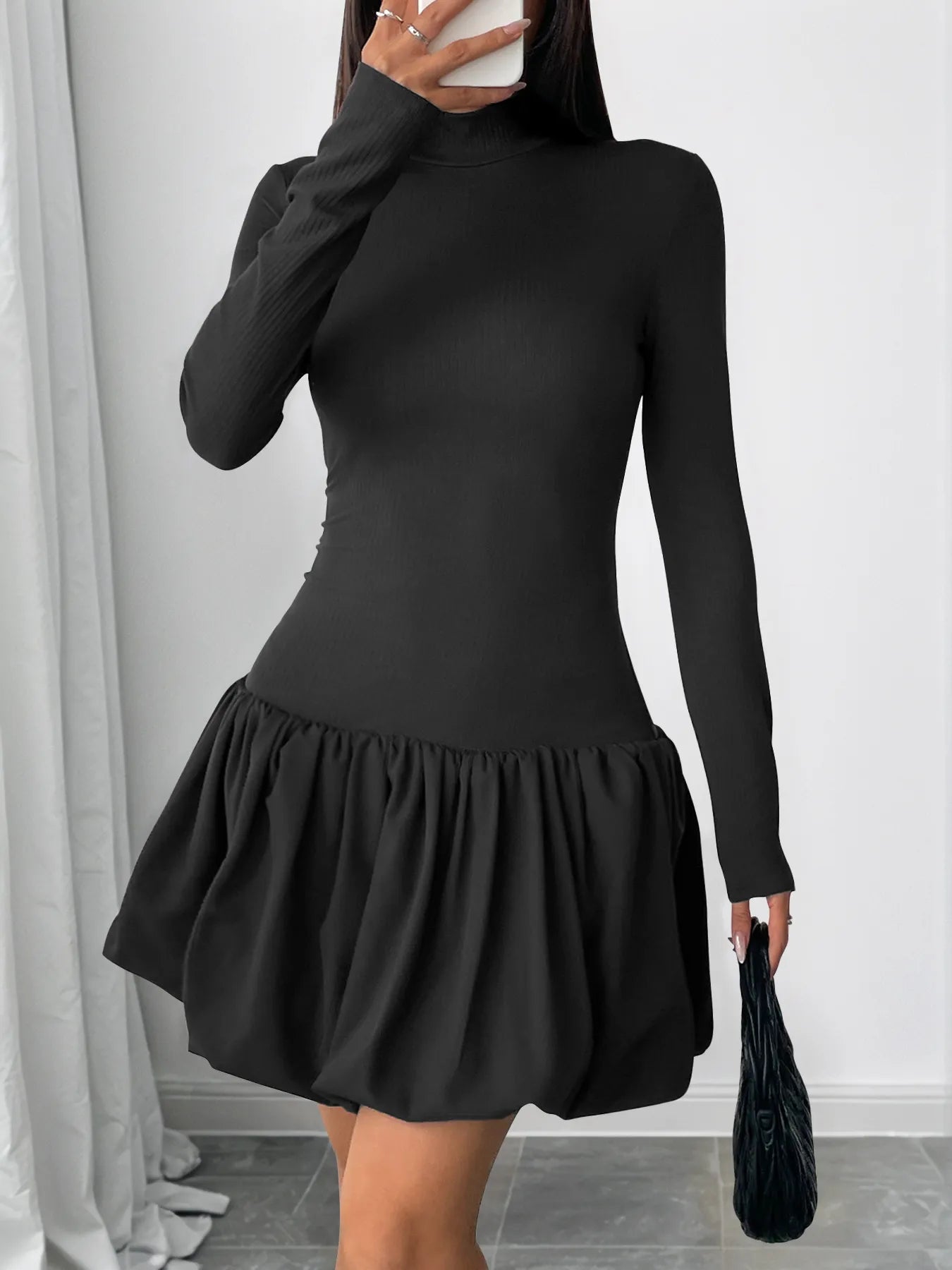 Person wearing a black dress with a ruffled skirt against a white background