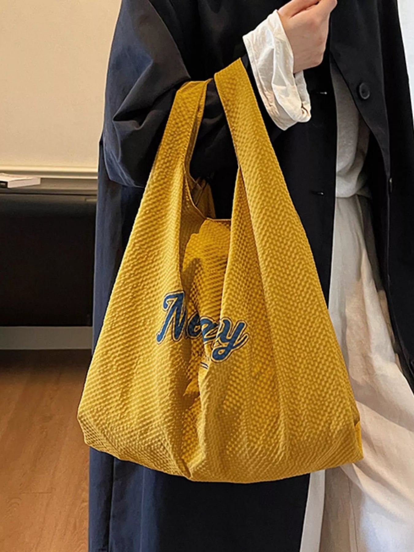 Person holding a yellow textured bag with 'Navy' branding.