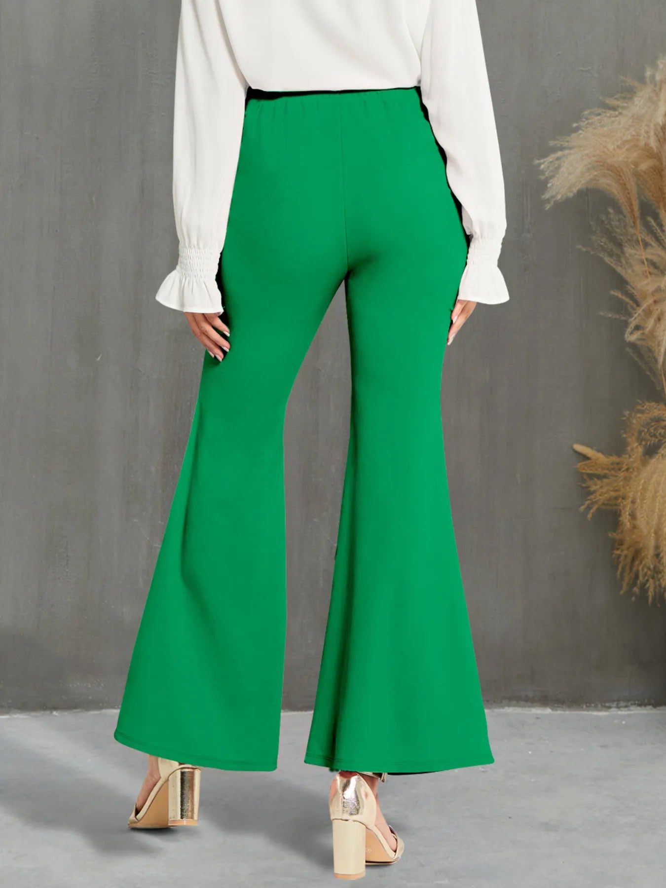 Green flared pants worn by a person against a gray background