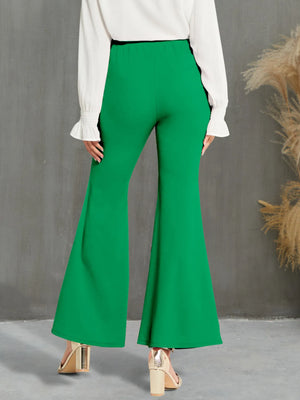Green flared pants worn by a person against a gray background