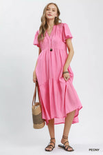 Woman wearing a pink dress holding a straw bag on a white background