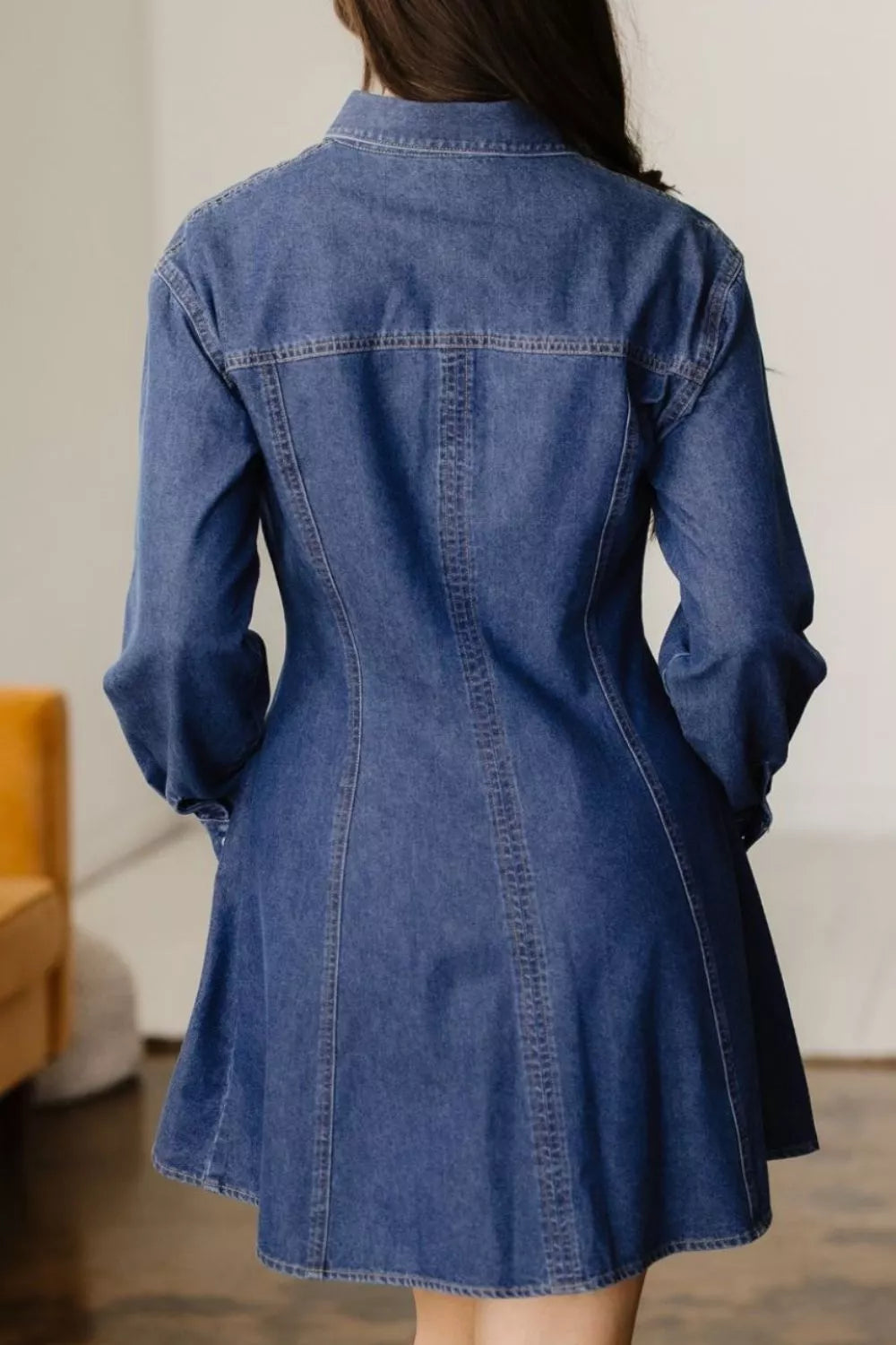 Blue denim dress worn by a person with a neutral background