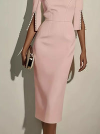 Pink dress with pearl details on sleeves against a neutral background