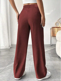Maroon wide-leg pants worn by a person in a minimal indoor setting.