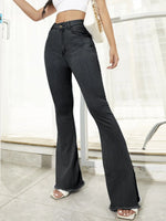 Person wearing black flared jeans in a minimal indoor setting