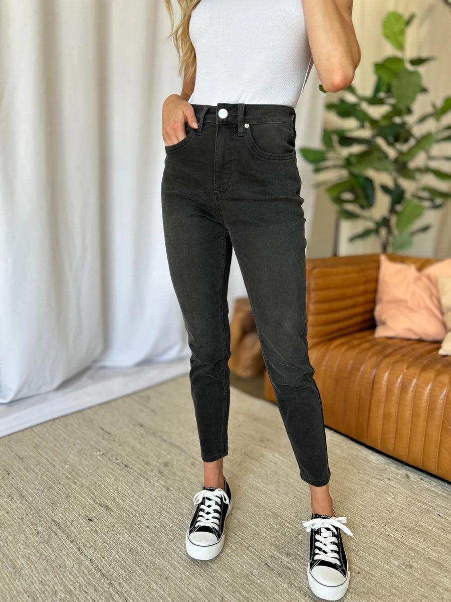 Person wearing black jeans and white sneakers in a living room setting